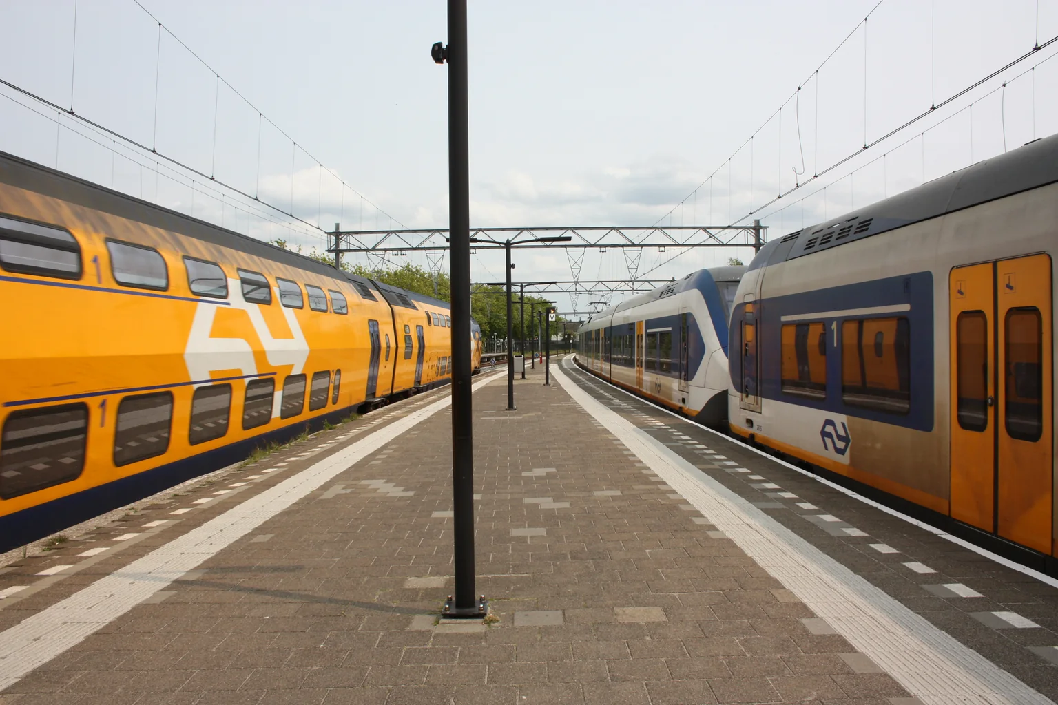 Een Sprinter en een passerende Intercity langs het perron van station Wormerveer in juni 2025